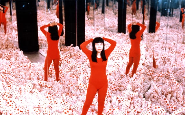 Kusama standing in her "Infinity Mirror Room─Phalli's Field" 1965